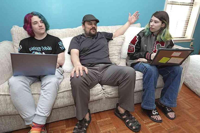 Tim Reiland, 42, center, is photographed with children Anakin Reiland, 15, left, and Zoe Reiland, 17, on Monday, March 10, 2025, in Clinton, Miss. Tim said he had no idea his children's previous schools in Oklahoma were using surveillance technology to monitor students. (AP Photo/Rogelio V. Solis)