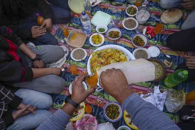 A man serves a juice while the Palestinians are preparing for Iftar, the rapidly roaring food during the Ramadan in a street of the war of the war population by Beit Lahia, Northern Gaza Strip, Saturday, March 15, 2025. (AP Photo/Jehad Alshrafi)