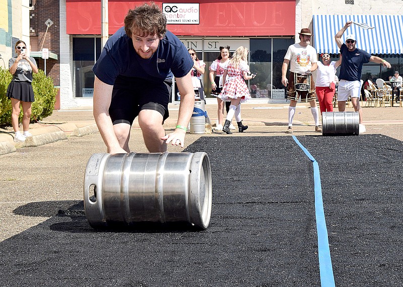 Brock Yates gets low to push a beer barrel on the Barrel Rolling course at Oktoberfest on Saturday afternoon, Oct. 5, 2024, in downtown Texarkana, Texas. The object of the game was to see who could roll a barrel the fastest down and back along the course. Oktoberfest is a fundraiser for Main Street Texarkana, which provides financial assistance for businesses and other agencies that support downtown revitalization. (Staff photo by Stevon Gamble)