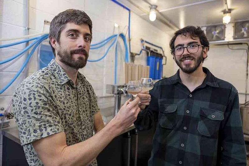 Scott Lafontaine, left, and Bernardo Guimaraes hold small glasses of beer made entirely with malted rice. They published a study in 2024 that identified several long-grain rice varieties with unique brewing qualities when malted. (Special to The Commercial/University of Arkansas System Division of Agriculture)