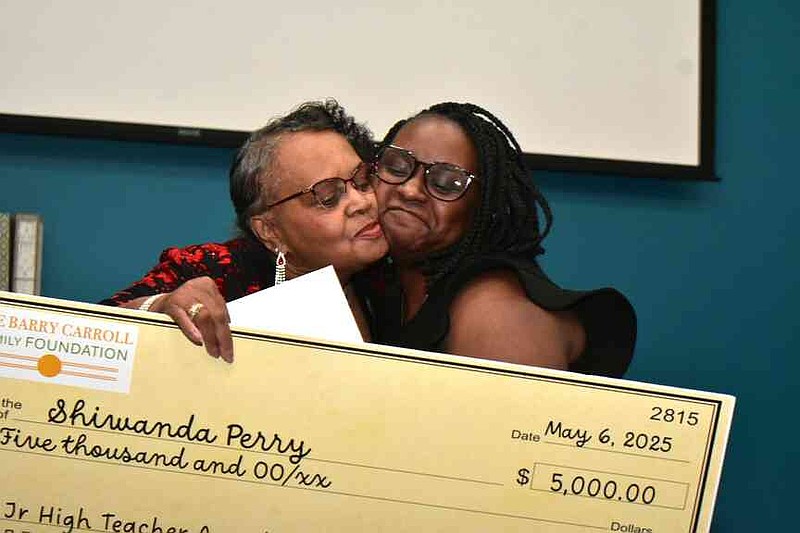 Mary Carroll, sister of NBA great Joe Barry Carroll, embraces Shiwanda Perry of Pine Bluff Junior High School and hands her a $5,000 check after Perry is named Joe Barry Carroll Award winner for junior high teachers in the PBSD. (Pine Bluff Commercial/I.C. Murrell)