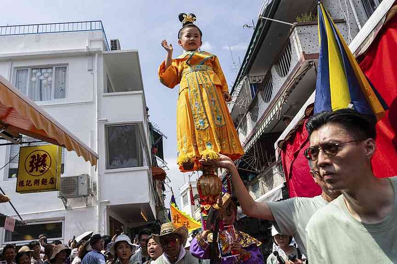 A child is hoisted up as participants take part in the Piu Sik Parade at the Bun Festival in Cheung Chau Island in Hong Kong, Monday, May 5, 2025. (AP Photo/Chan Long Hei)