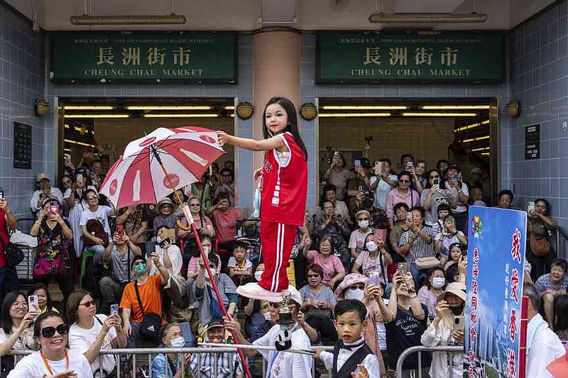 A child is hoisted up as participants take part in the Piu Sik Parade at the Bun Festival in Cheung Chau Island in Hong Kong, Monday, May 5, 2025. (AP Photo/Chan Long Hei)