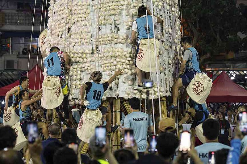 Participants collect buns from a tower covered with plastic buns during the Bun Festival in Cheung Chau Island in Hong Kong, Tuesday, May 6, 2025. (AP Photo/Chan Long Hei)