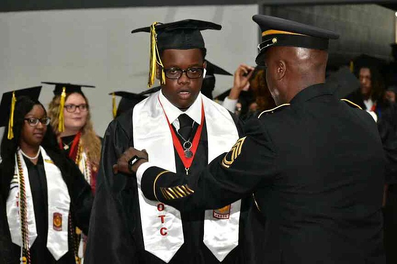 JROTC Sgt. Jimmy Stocker adjusts the graduation stole of Jerimiah Robinson. (Pine Bluff Commercial/I.C. Murrell)