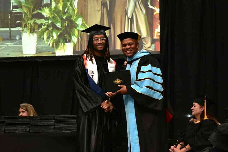 Basketball standout Tobias Prall receives his degree from SEARK President Tyrone Jackson. (Pine Bluff Commercial/I.C. Murrell)