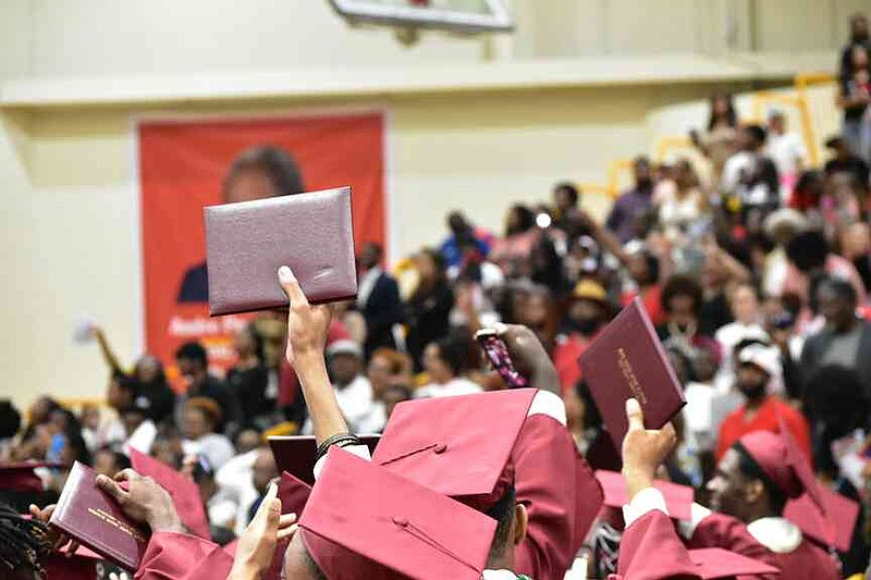 Graduates raise their diplomas in celebration. (Pine Bluff Commercial/I.C. Murrell)