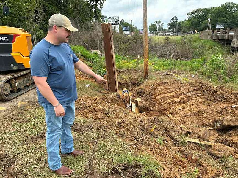 Sheridan Mayor Cain Nattin points Monday to the area where two 10-inch water mains were joined to give 3,000 to 4,000 customers access to water. (Pine Bluff Commercial/Byron Tate)