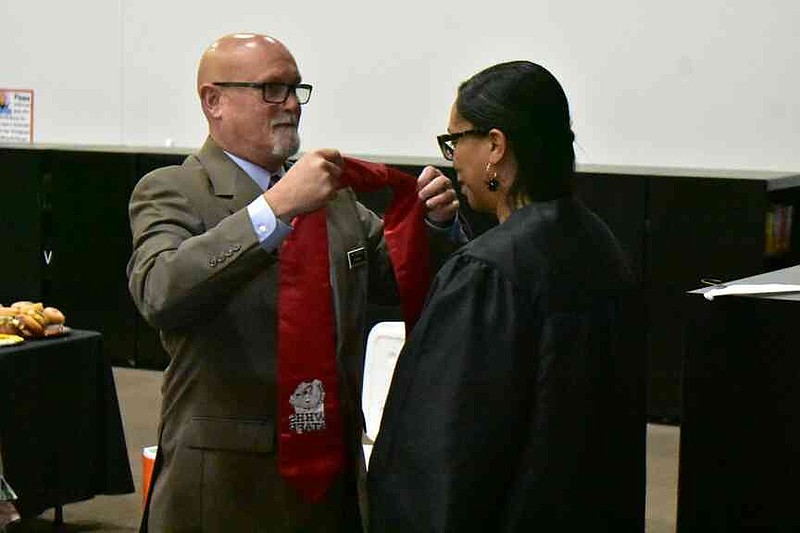 White Hall High Principal Nathan Sullivan robes recent University of Arkansas graduate Leslie Mitchell and presents her with a White Hall Bulldog stole. (Pine Bluff Commercial/I.C. Murrell)