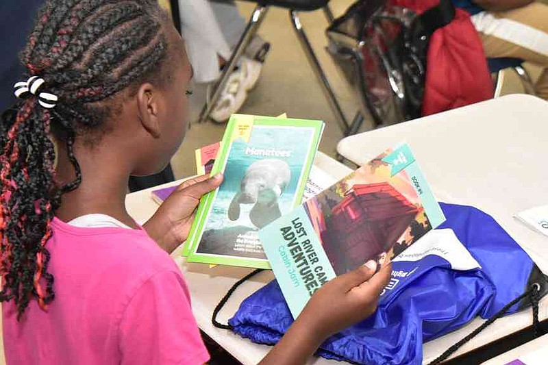 A young third-grader checks out the collection of grade-level books she will take home for the summer. (Pine Bluff Commercial/I.C. Murrell)