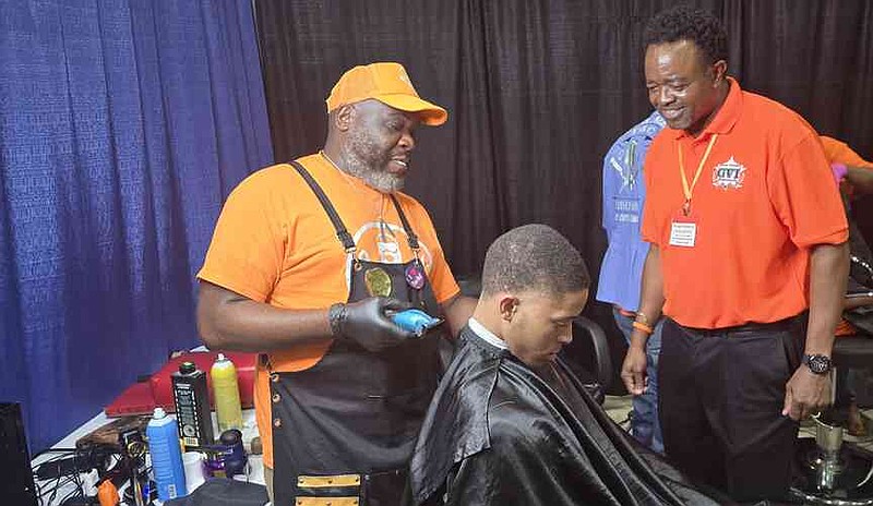 GVI program manager Kevin Crumpton, right, checks out the free haircut by barber Gregory Farris, during the Go Orange Day event. (Pine Bluff Commercial/Eplunus Colvin)