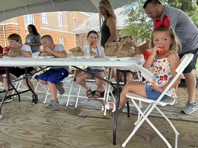 Weylyn McDaniel, 4, of Wilmar, takes a bite into a tomato at the 69th Bradley County Pink Tomato Festival Saturday as she competes for the tomato-eating title. (Pine Bluff Commercial/Byron Tate)