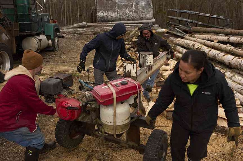 Workers with the Sustainable Energy for Galena, Alaska, from left, James Strong, Nathan Moses, Morris Demoski and Marissa McCarty move a log splitting machine before cutting wood to deliver to elders in the community Monday, May 19, 2025, in Galena. (AP Photo/John Locher)