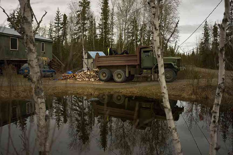 Nathan Moses, from left, Morris Demoski and Marissa McCarty deliver wood to an elder Monday, May 19, 2025, in Galena, Alaska. (AP Photo/John Locher)