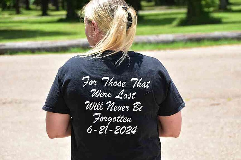 Wanda Gaskey of Thornton displays the back of her T-shirt remembering those lost in the June 21, 2024, mass shooting at The Mad Butcher grocery store in Fordyce. (Pine Bluff Commercial/I.C. Murrell)