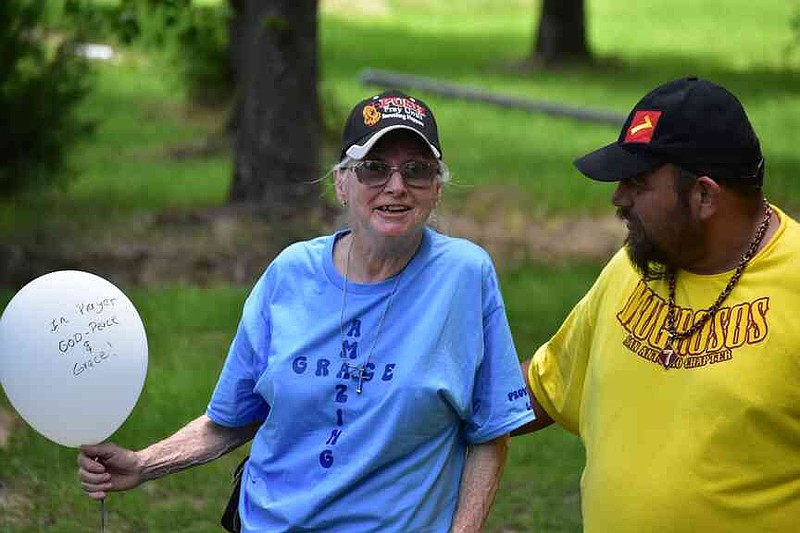 Betty Strong of Fordyce holds a balloon and makes comments as Dustin Samaniego of Smackover encourages her at a balloon release near a Fordyce ballpark Saturday, June 21, 2025. The balloon release honored the victims of a June 21, 2024, mass shooting at The Mad Butcher grocery store in Fordyce. (Pine Bluff Commercial/I.C. Murrell)