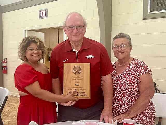 Bradley County Pink Tomato Festival Chairman Nora Pacheco, left, presents a plaque to the 2025 Bradley County Farm Family of the Year — Richard and Karen McDougald. The award was presented June 14 during the All-Tomato Luncheon at First United Methodist Church in Warren. (Special to The Commercial/University of Arkansas System Division of Agriculture)