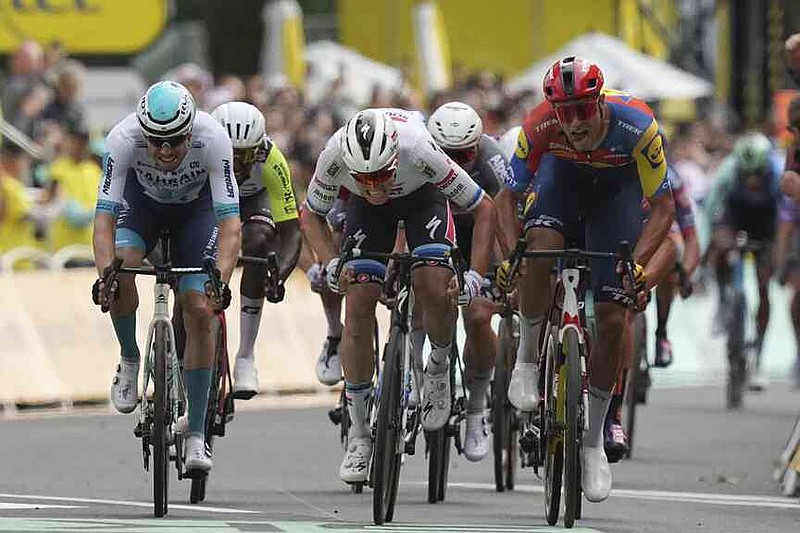 Belgium's Tim Merlier, center, and Italy's Jonathan Milan, right, sprint to the finish line during the third stage of the Tour de France cycling race over 178.3 kilometers (110.8 miles) with start in Valenciennes and finish in Dunkerque, France, Monday, July 7, 2025. (AP Photo/Thibault Camus)