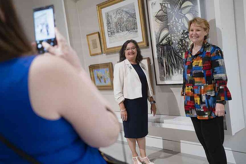 Rep. Diana Gonzalez Worthen (from left) and Rep. Denise Garner pose for a phone photo Thursday during a ribbon cutting ceremony for a new Crystal Bridges satellite gallery at the Northwest Arkansas National Airport. Northwest Arkansas National Airport (XNA) and Crystal Bridges Museum of American Art invited press to attend a ribbon cutting ceremony celebrating the opening of the museum's new satellite gallery in the airport terminal. Visit nwaonline.com/photo for today's photo gallery. (NWA Democrat-Gazette/Charlie Kaijo)