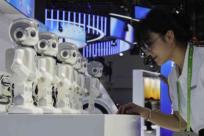 An exhibitor gives a command to a Ubtech humanoid robot at a booth during the 3rd China International Supply Chain Expo at the China International Exhibition Center, in Beijing, China, Friday, July 18, 2025. (AP Photo/Mahesh Kumar A.)