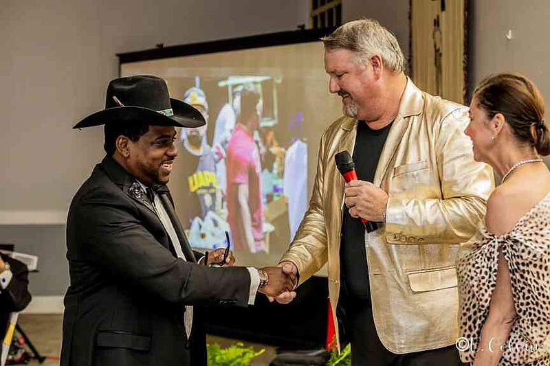 Sharri and Bill Jones, right and center, of Sissy's Log Cabin, express their love for Sheriff Lafayette Woods Jr. and his family while presenting him with a cowboy hat and sunglasses. (Pine Bluff Commercial/Eplunus Colvin)