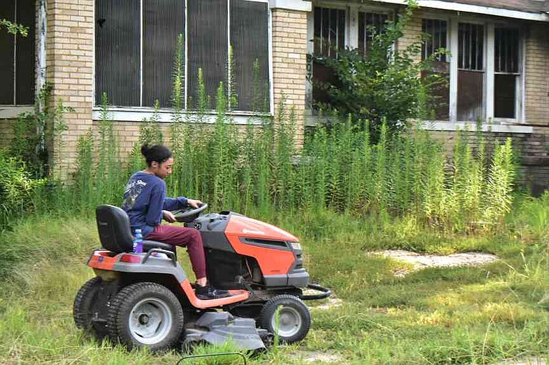Miranda Cosner drives a riding lawnmower on a vacant lot. (Pine Bluff Commercial/I.C. Murrell)