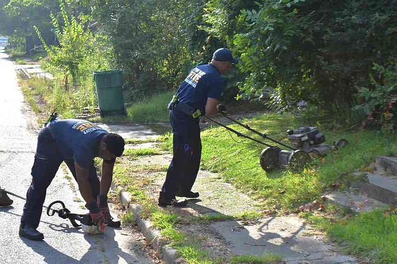 Pine Bluff firefighters Curtis Standoak, left, and Juan Ventress mow and trim property just off Elm Street. (Pine Bluff Commercial/I.C. Murrell)