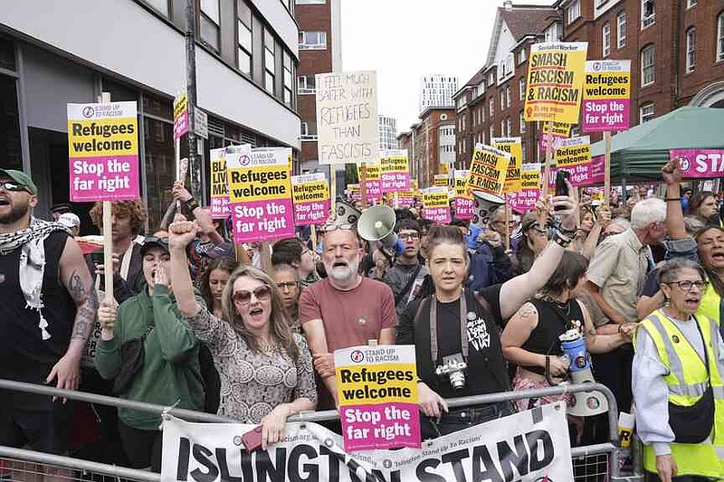 Stand Up To Racism counter protesters gather outside the Thistle City Barbican Hotel in central London, which houses asylum seekers, Saturday Aug. 2, 2025. (PA via AP)