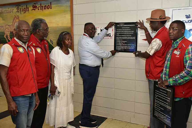 Pine Bluff High School Principal Ronald Laurent, third from right, helps Pine Bluff-area pastors Leon Jones (from left), Jesse Turner, Saint Mary Harris, Alexander Watkins Sr. and James Hill Jr. display a framed poster of The Ten Commandments. (Pine Bluff Commercial/I.C. Murrell)