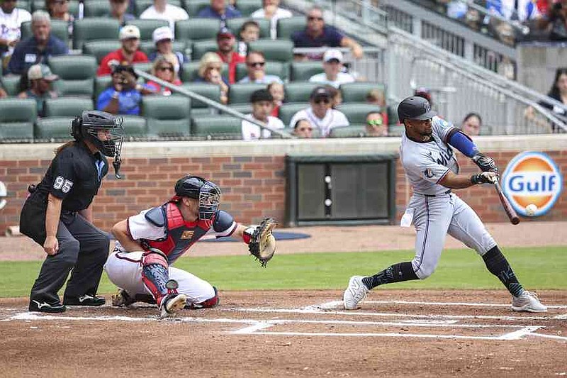 Home plate umpire Jen Pawol, left, watches Miami Marlins' Xavier Edwards, right, swing at a pitch in the first inning of a baseball game against the Atlanta Braves, Sunday, Aug. 10, 2025, in Atlanta. (AP Photo/Colin Hubbard)