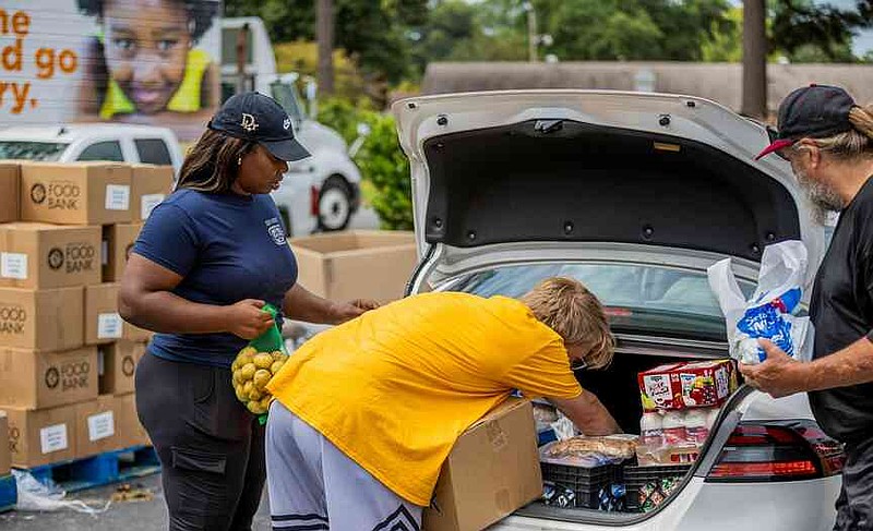 Volunteers pack free groceries in the trunk of a car. (Pine Bluff Commercial/Eplunus Colvin)