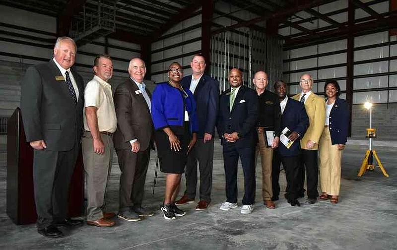 From left: Watson Chapel School District board members Alan Frazier and Donnie Hartsfield, Bobby Gosser of Baldwin & Shell Construction Co., Pine Bluff Mayor Vivian Flowers, Scott Pittillo of Relyance Bank, WCSD Superintendent Keith McGee, state Reps. Mike Holcomb and Glenn Barnes, Steve Elliott of Lewis Architects Engineers and WCSD assistant superintendent Aleta Posey take a group photo on the arena floor of Relyance Bank Arena under construction. (Pine Bluff Commercial/I.C. Murrell)