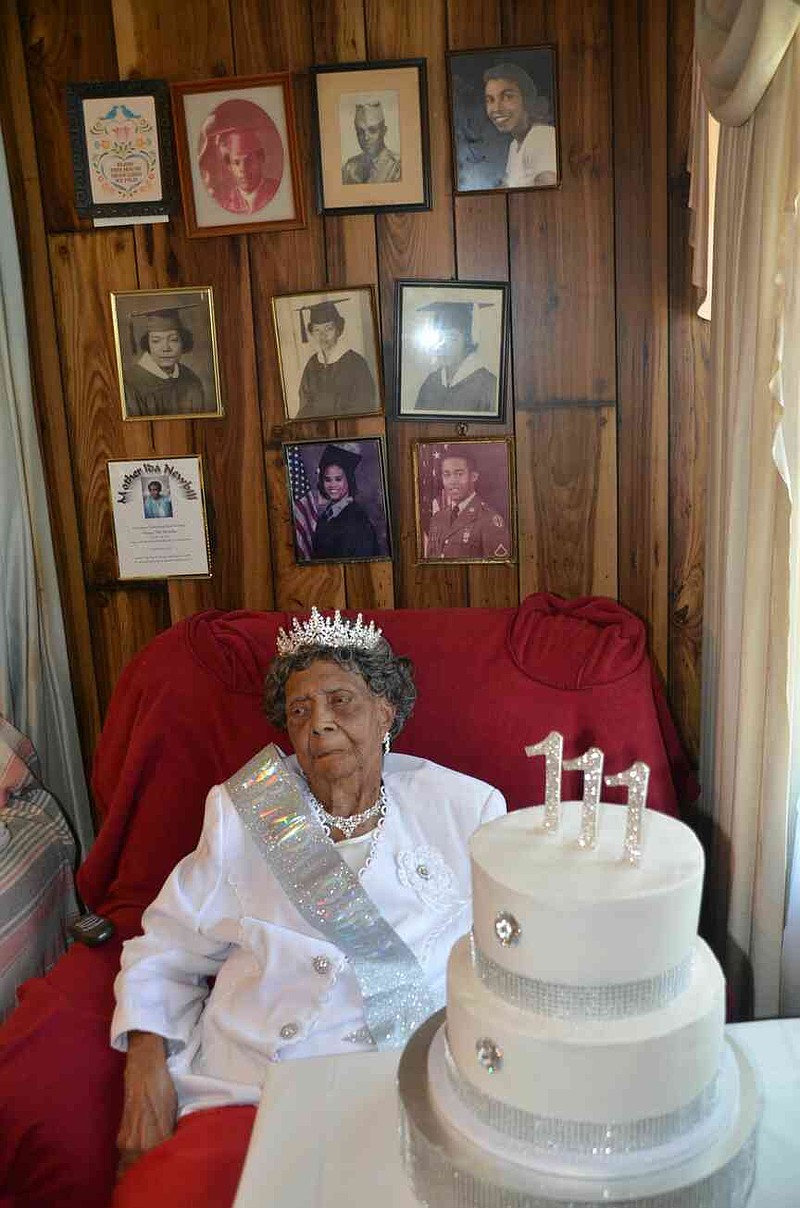 Surrounded by photos of her six children and a house full of well-wishers is Ida Newbill of Eudora, who celebrated her 111th birthday with a lemon cake. U.S. Congressman Rick Crawford said Newbill had been confirmed as the oldest living person in Arkansas. (Special to The Commercial/Richard Ledbetter)