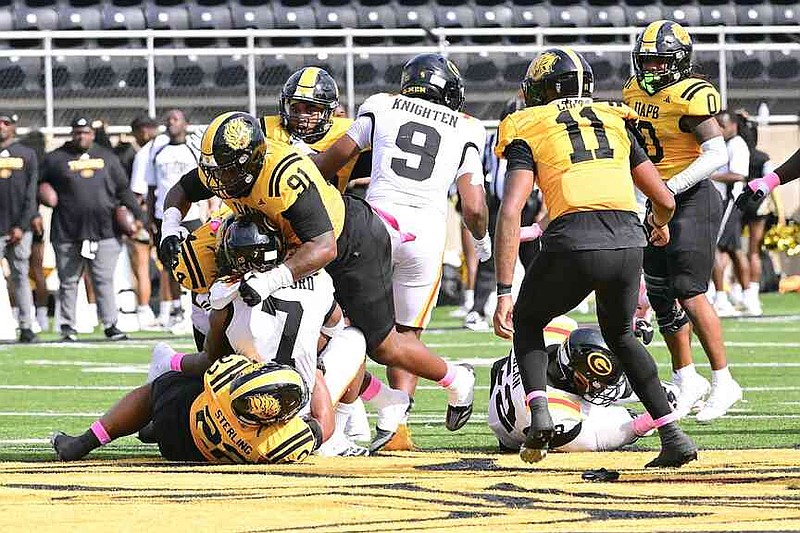 UAPB defensive lineman Marc Guelache (91), safety Quintin Sterling (22) and linebacker Derrick Murdock (44) team up to tackle Grambling State running back Tre Bradford (7). (Special to the Commercial/William Harvey)