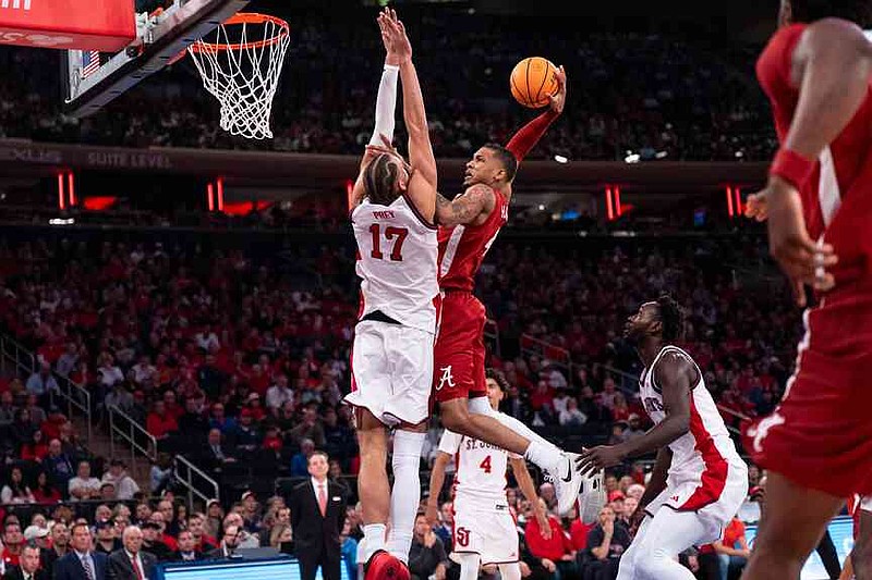 Alabama guard Davion Hannah (4), defended by St. John’s forward Rubén Prey (17), attempts a dunk during the first half of an NCAA college basketball game, Saturday, Nov. 8, 2025, in New York. (AP Photo/Angelina Katsanis)