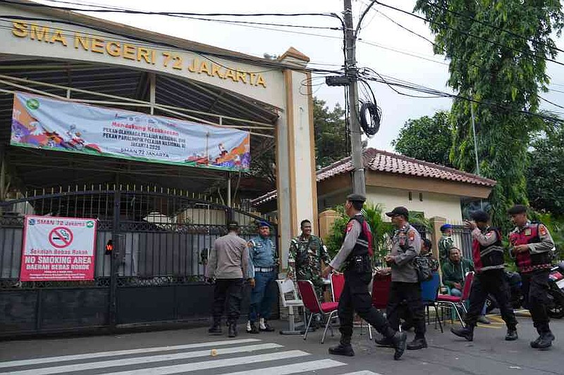 Police officers and military personnel stand guard at the gate of a school after explosions in Jakarta, Indonesia, Saturday, Nov. 8, 2025. (AP Photo/Achmad Ibrahim)