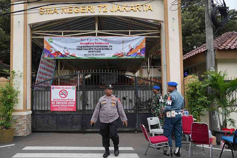 Police officers and military personnel stand guard at the gate of a school after explosions in Jakarta, Indonesia, Saturday, Nov. 8, 2025. (AP Photo/Achmad Ibrahim)