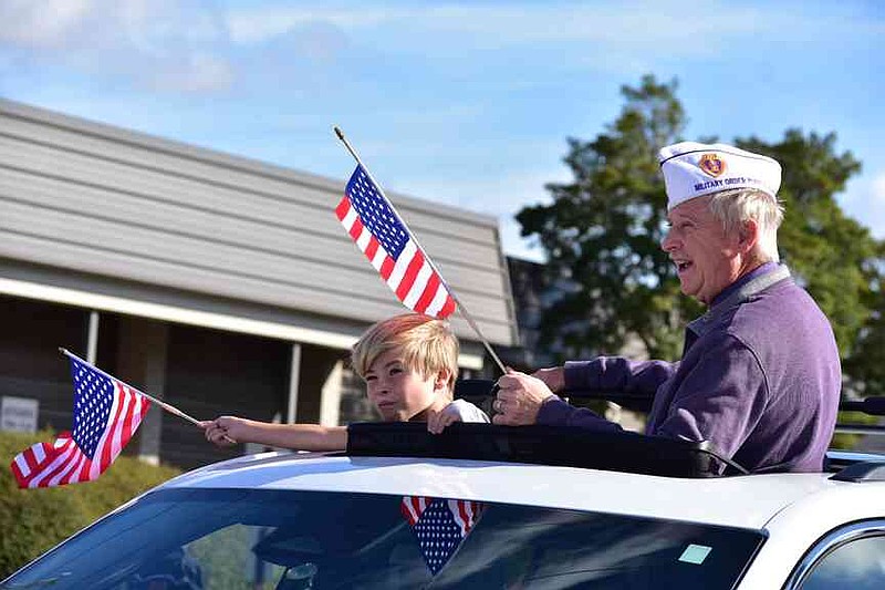 A Purple Heart veteran and a young boy take off inside a vehicle for the Pine Bluff Regional Veterans Parade on Saturday, Nov. 15, 2025. (Pine Bluff Commercial/I.C. Murrell)