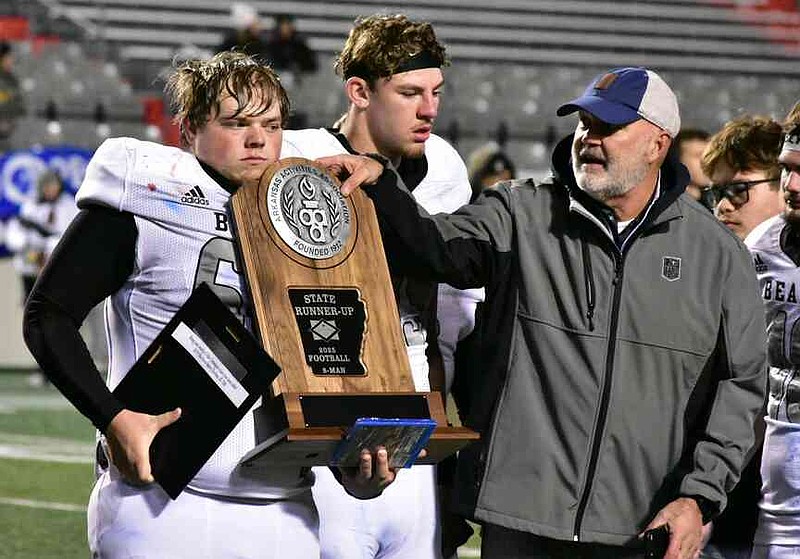 Woodlawn center/defensive tackle Dakota Campbell receives the Brandon Burlsworth Award and state eight-man football runner-up trophy from Steve Roberts of the Arkansas Activities Association as tight end Beau Watson looks on Thursday, Dec. 4, 2025, at War Memorial Stadium in Little Rock. (Pine Bluff Commercial/I.C. Murrell)