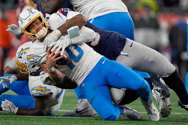 Los Angeles Chargers quarterback Justin Herbert (10) is sacked by New England Patriots linebacker Anfernee Jennings, rear, in the second half of an NFL wild-card playoff football game in Foxborough, Mass., Sunday, Jan. 11, 2026. (AP Photo/Charles Krupa)
