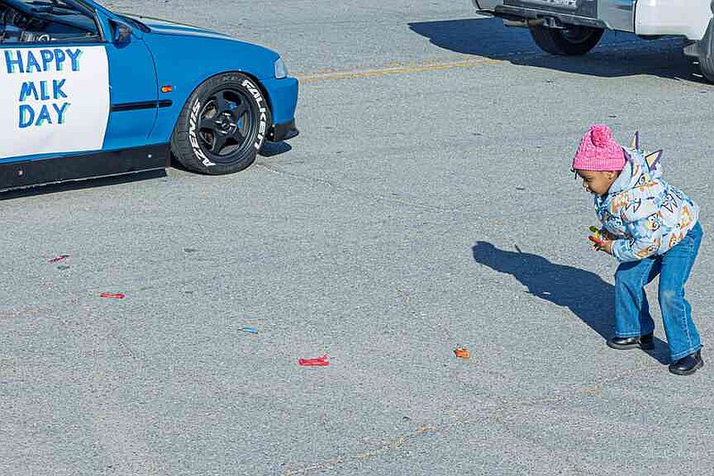 A child collects candy near a decorated vehicle during the Marade. (Pine Bluff Commercial/Eplunus Colvin)