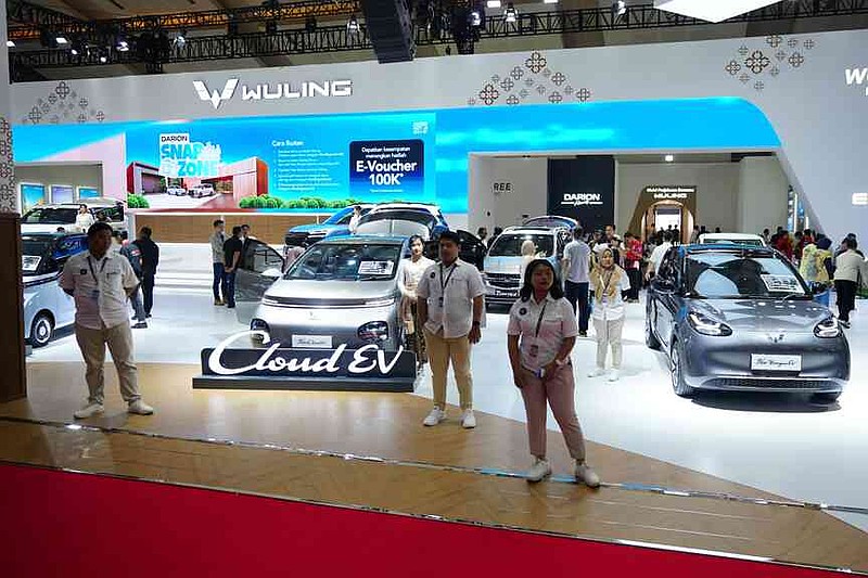 Sales people stand near electric vehicles made by Chinese auto manufacturer Wuling during a motor show in Jakarta, Indonesia Saturday, Feb. 7, 2026. (AP Photo/Tatan Syuflana)