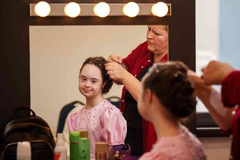 Marusika Burlaca sits while getting her hair done, before the SEEN Anonymous Seamstresses Gala, an event organised by the Down Plus Bucharest, an NGO supporting youngsters with Down Syndrome and other intellectual disabilities, in Bucharest, Romania, Wednesday, March 18, 2026, ahead of the World Down Syndrome Day, on March 21. (AP Photo/ Vadim Ghirda)