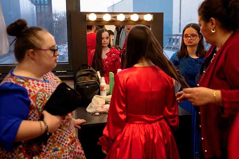 Teodora Brezeanu, looks in the mirror while getting her hair done, before the SEEN Anonymous Seamstresses Gala, an event organised by the Down Plus Bucharest, an NGO supporting youngsters with Down Syndrome and other intellectual disabilities, in Bucharest, Romania, Wednesday, March 18, 2026, ahead of the World Down Syndrome Day, on March 21. (AP Photo/Andreea Alexandru)