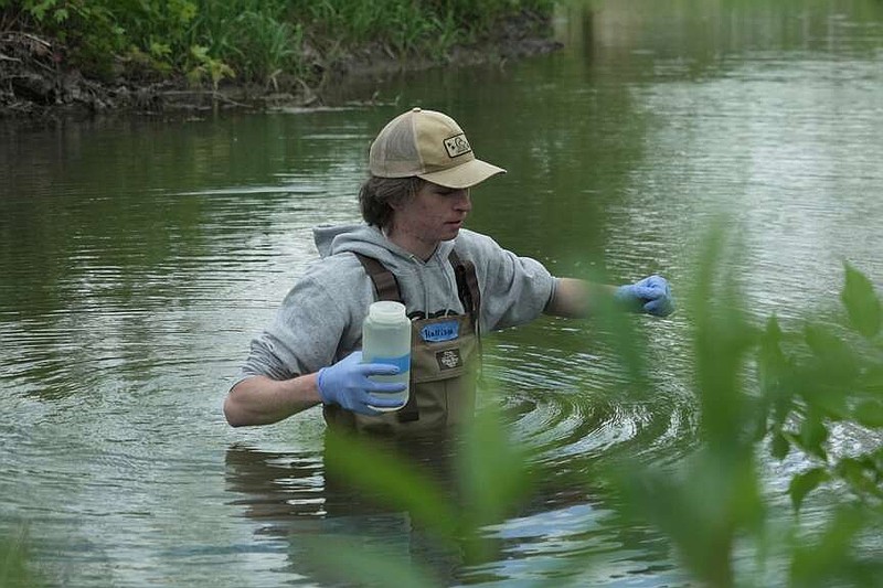 Drake University student Harrison Ziegler holds a bottle as he collects a water sample Wednesday, May 6, 2026, in Des Moines, Iowa. (AP Photo/Brittany Peterson)
