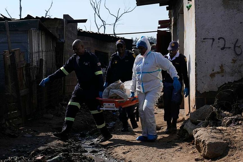 Police officers carry the body of a man on a stretcher after a mass shooting in an informal settlement in the Cleveland suburb of Johannesburg, South Africa, on Wednesday, June 10, 2026. (AP Photo/Themba Hedebe)