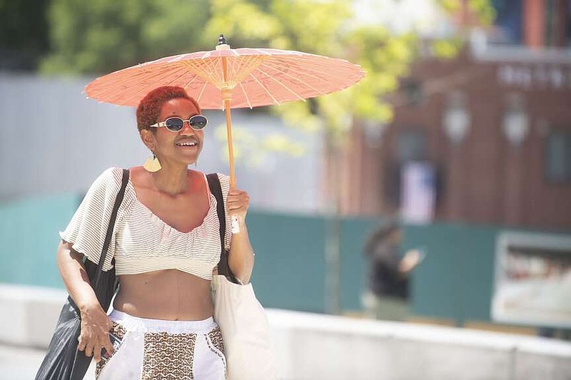 ChyNa Nellon of Fayetteville uses a parasol for shade Saturday June 20, 2026 during the Juneteenth celebrations hosted by the University of Arkansas and the NWA Juneteenth Planning Committee in the Upper Ramble in Fayetteville. The free community event featured live music, games, giveaways, and family-friendly activities. Visit nwaonline.com/photo for today's photo gallery. (NWA Democrat-Gazette/J.T. Wampler)