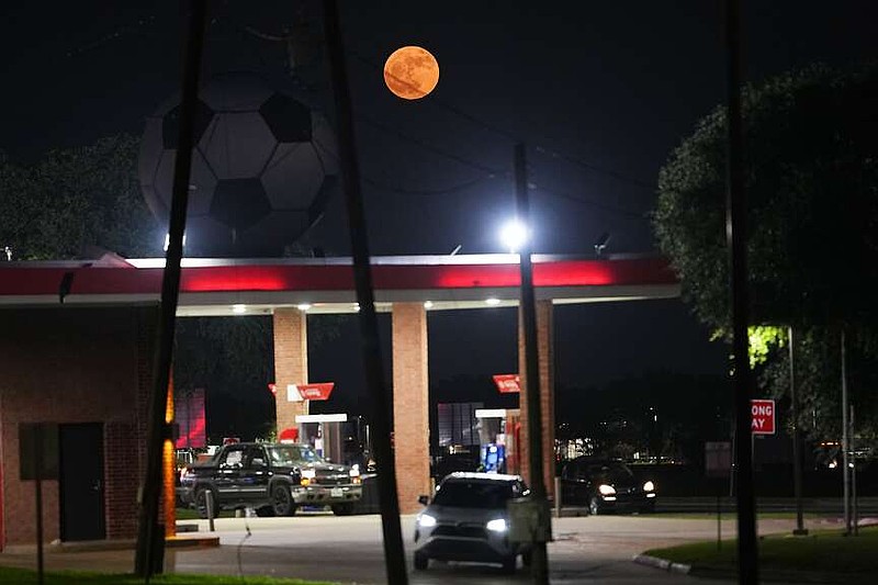 The full moon rises behind a large soccer ball atop a gas station in honor of the World Cup soccer tournament in Arlington, Texas, near Dallas, Monday, June 29, 2026. (AP Photo/Julio Cortez)