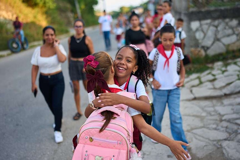 Girls hug as they arrive to school for their first day back to classes in Minas, Cuba's Havana province, Tuesday, Sept. 1, 2026. (AP Photo/Ramon Espinosa)