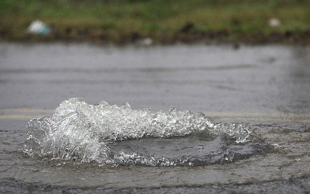 Water bubbles out of a manhole cover in this file photo.